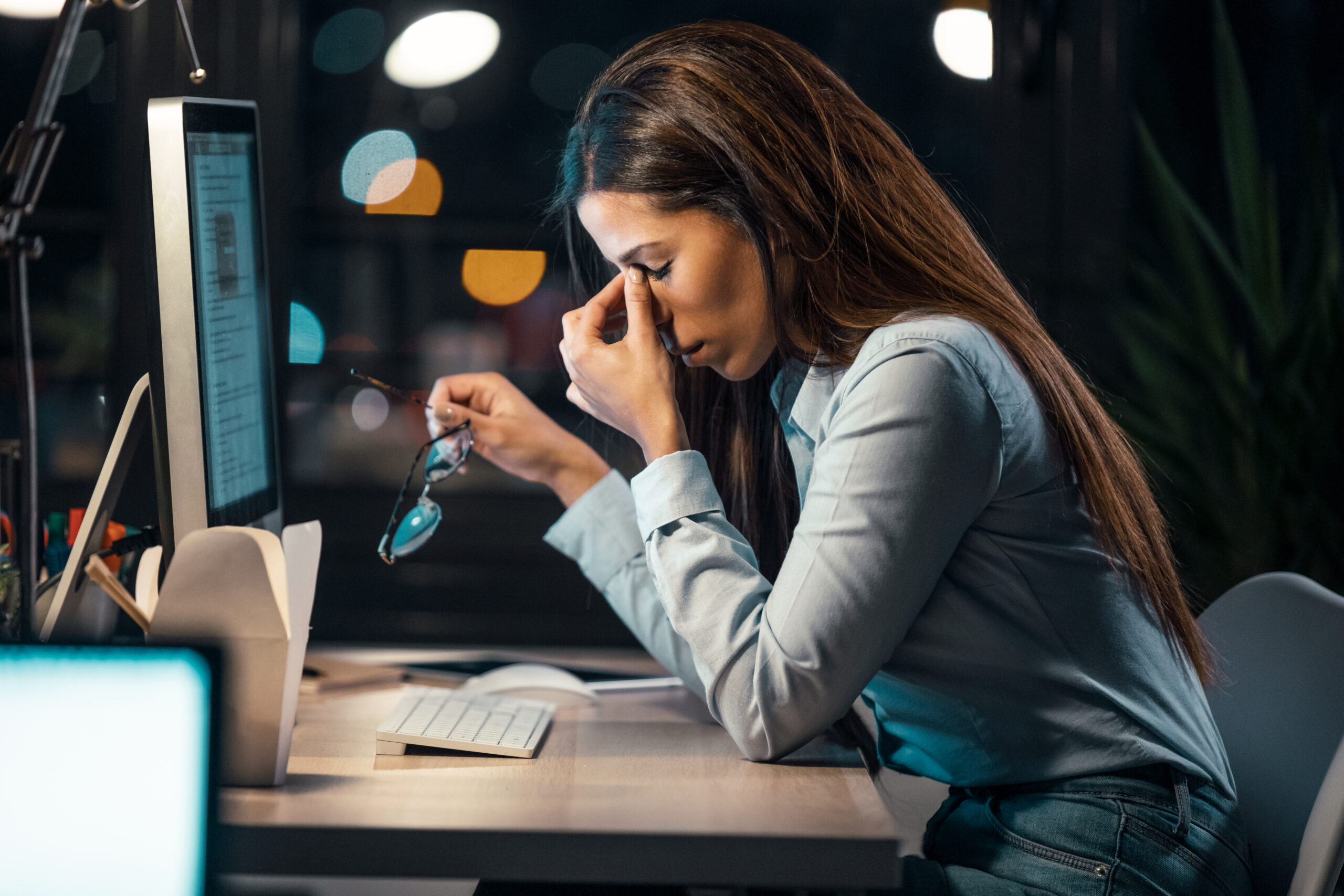 Woman at work sitting in front her computer rubbing her eyes